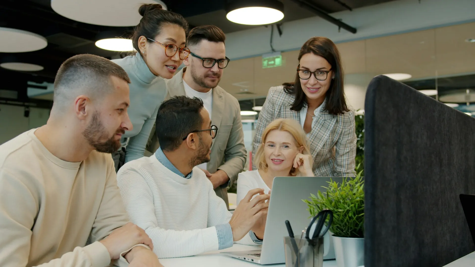 A product team gathered around a laptop reviewing work together