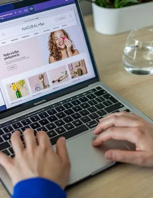 Hands typing on a laptop showing an online store
